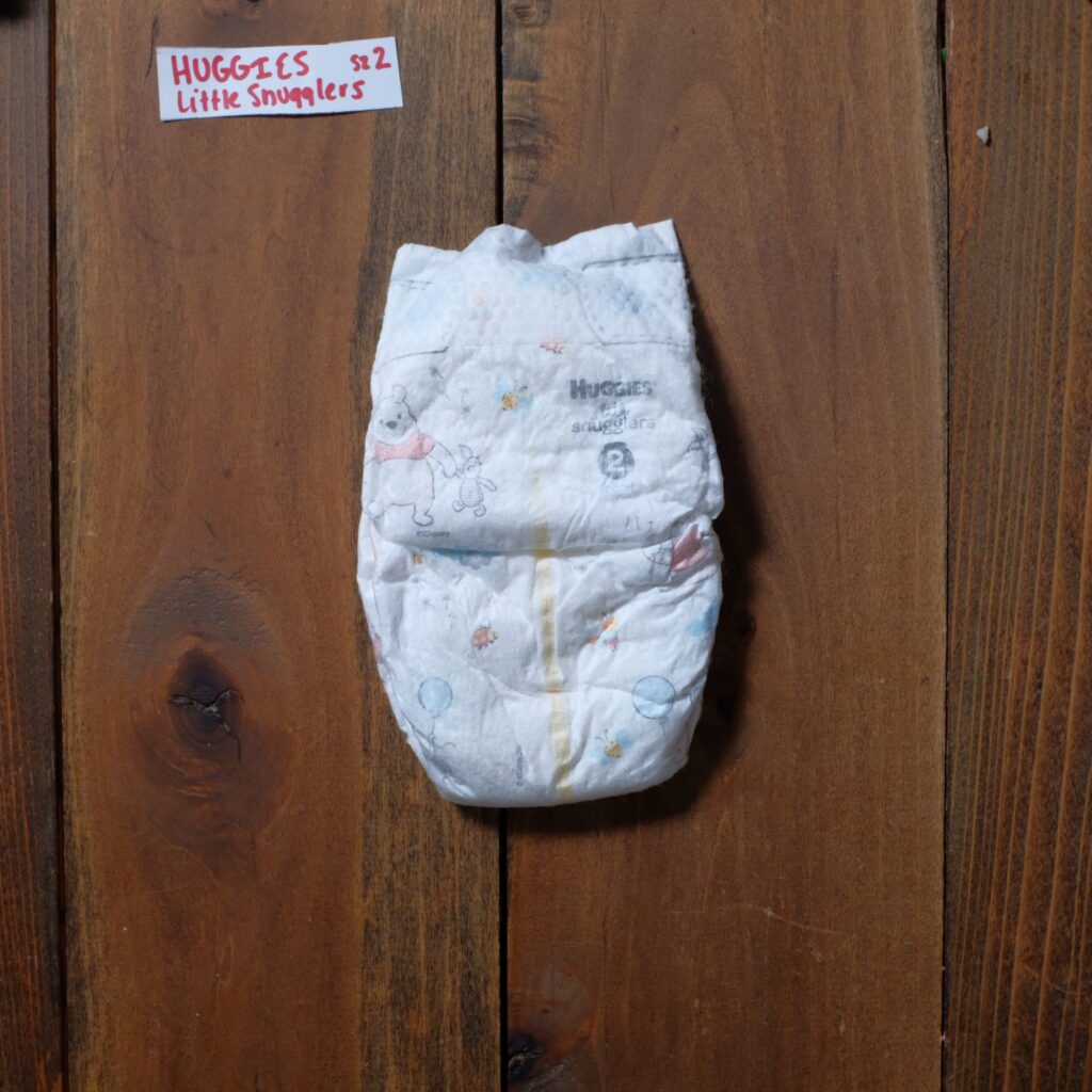 front of a huggies little snugglers diaper with winnie the pooh design against a wooden backgorund