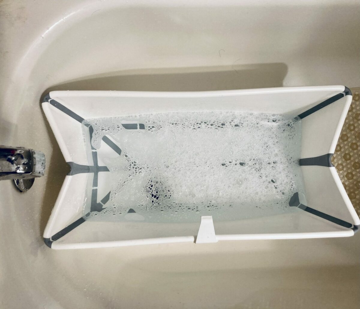 Overhead view of the Stokke Flexi baby bath filled with water and bubbles