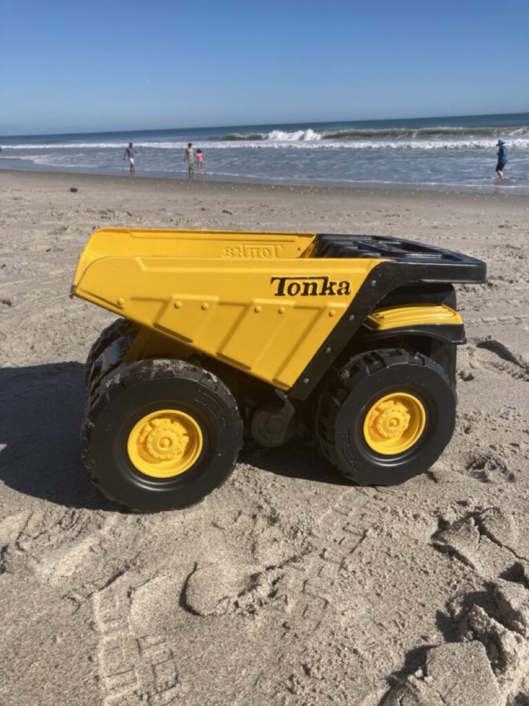 big tonka dump truck at the beach with the ocean in the background