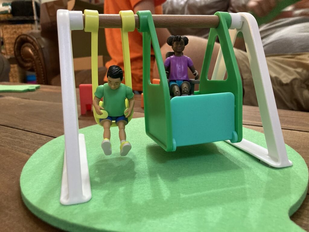 Lovevery friends and swing toy, showing two kid figurines in a little toy swing set