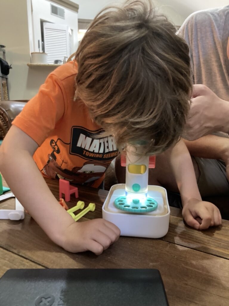 toddler using the lovevery microscope with his face down looking into the microscope