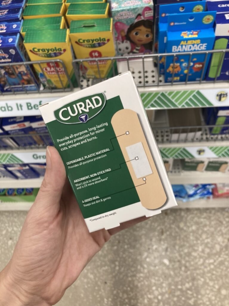 a hand holding a box of curad bandaids