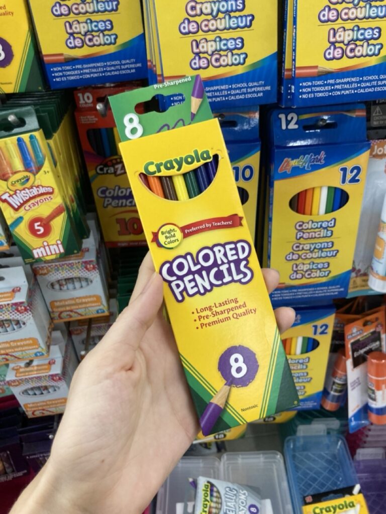 a hand holding a box of colored pencils