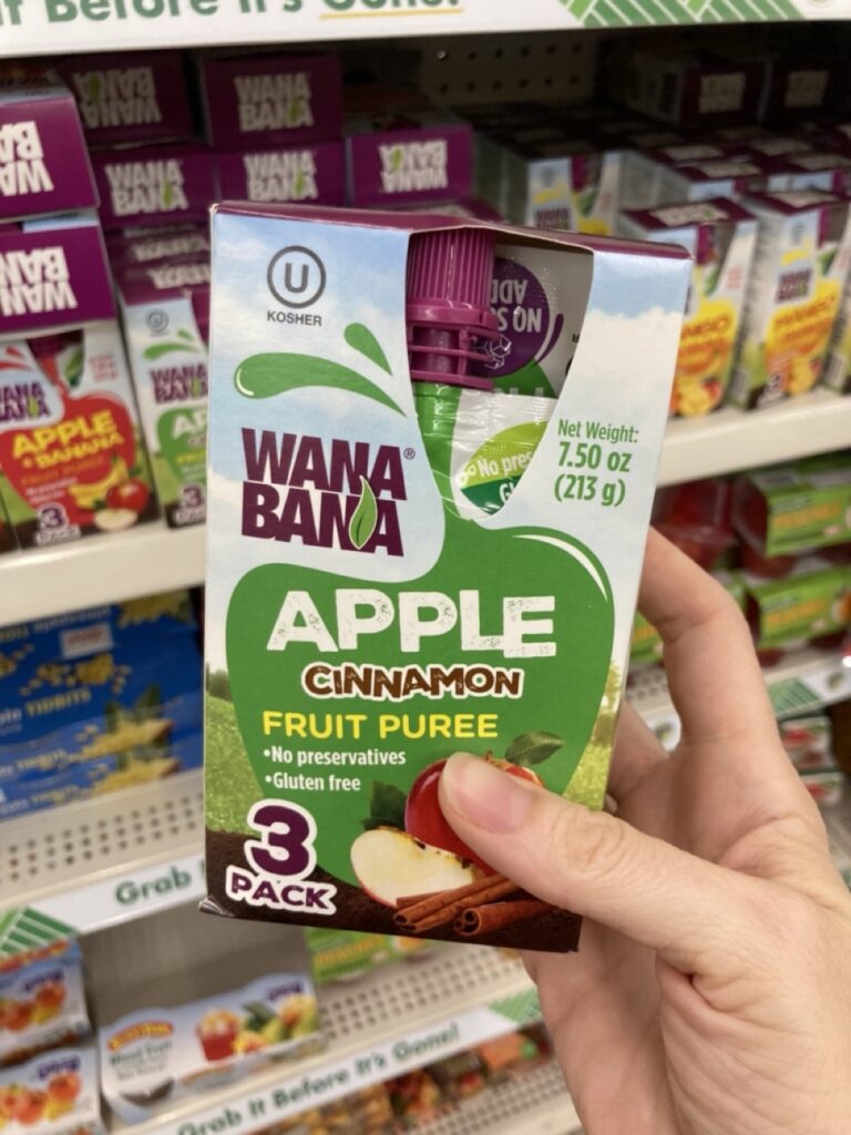a hand holding a box of apple sauce pouches