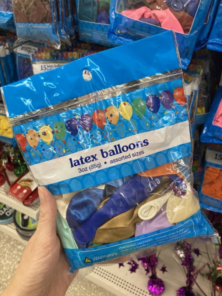 a hand holding a package of multicolor latex balloons