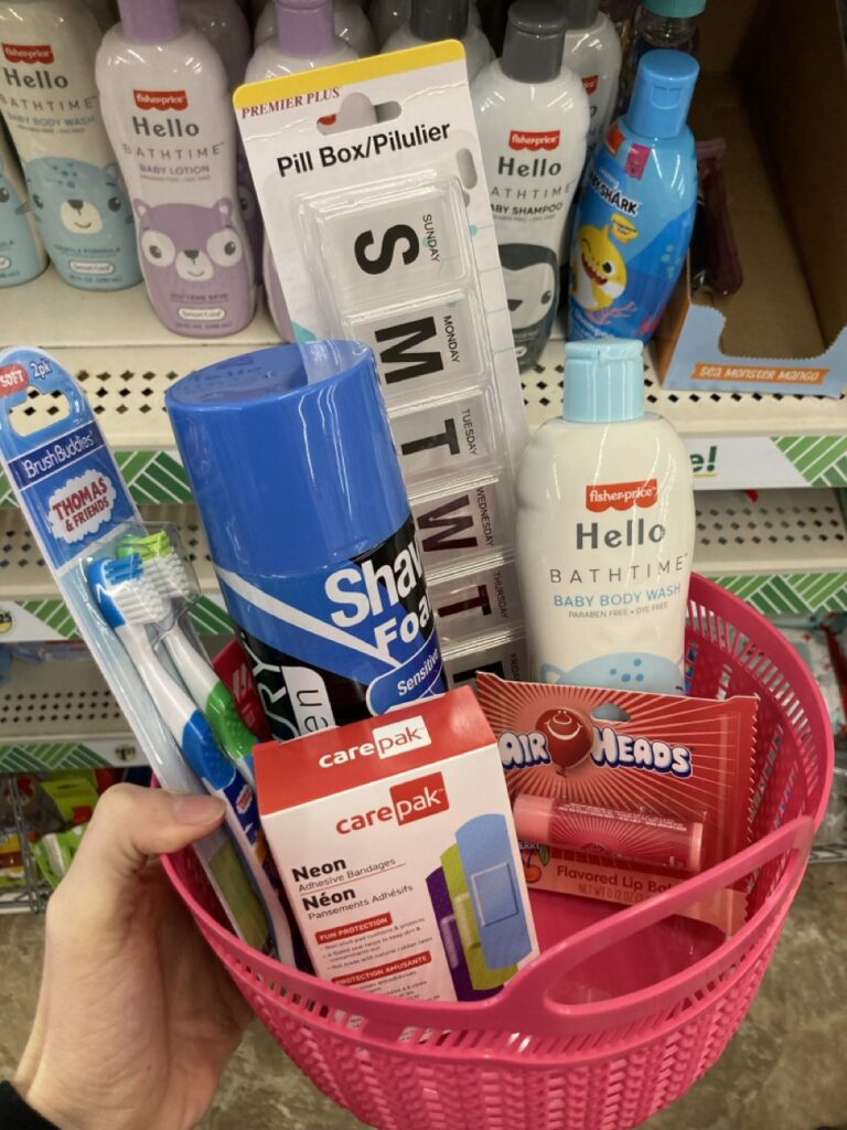 This picture is of a small plastic basket filled with bath products being held by a hand in an aisle at the dollar tree