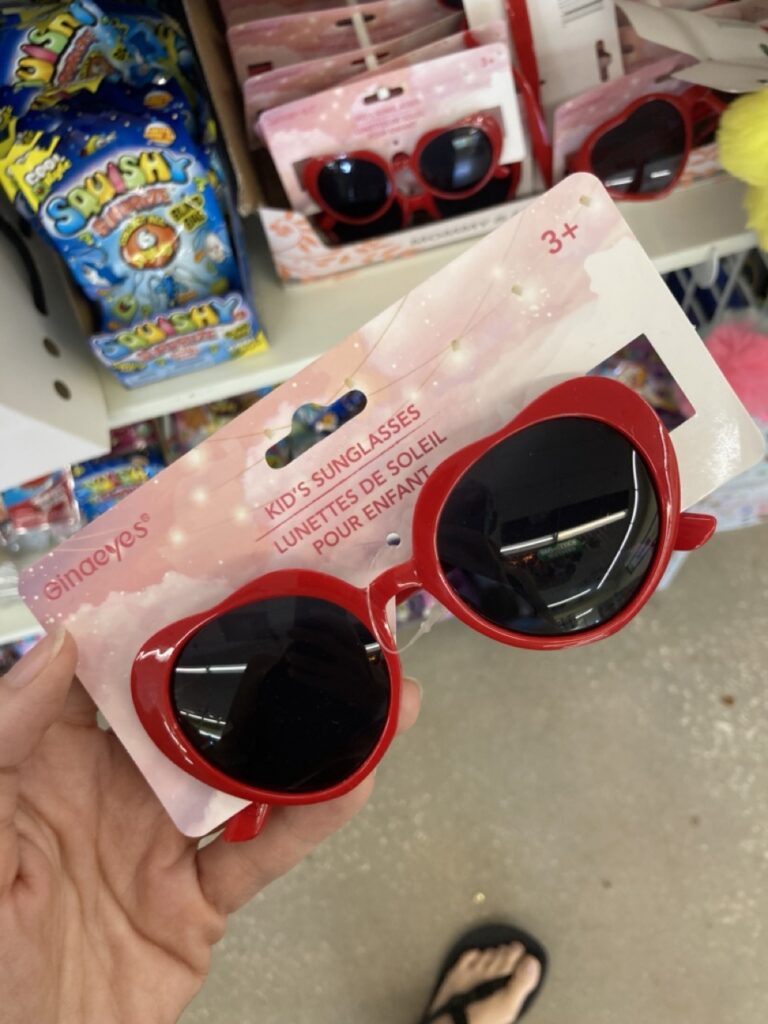 a hand holding up a pair of red heart shaped sunglasses