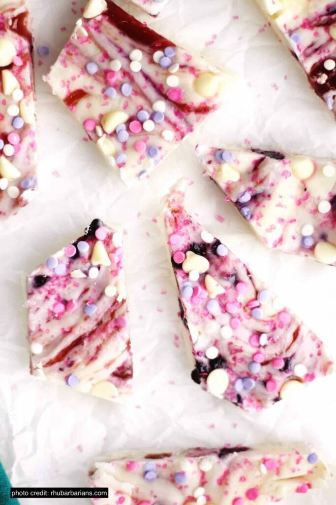 This shows pieces of greek yogurt bark on a plate with swirls of pink and pink sprinkles on top. 