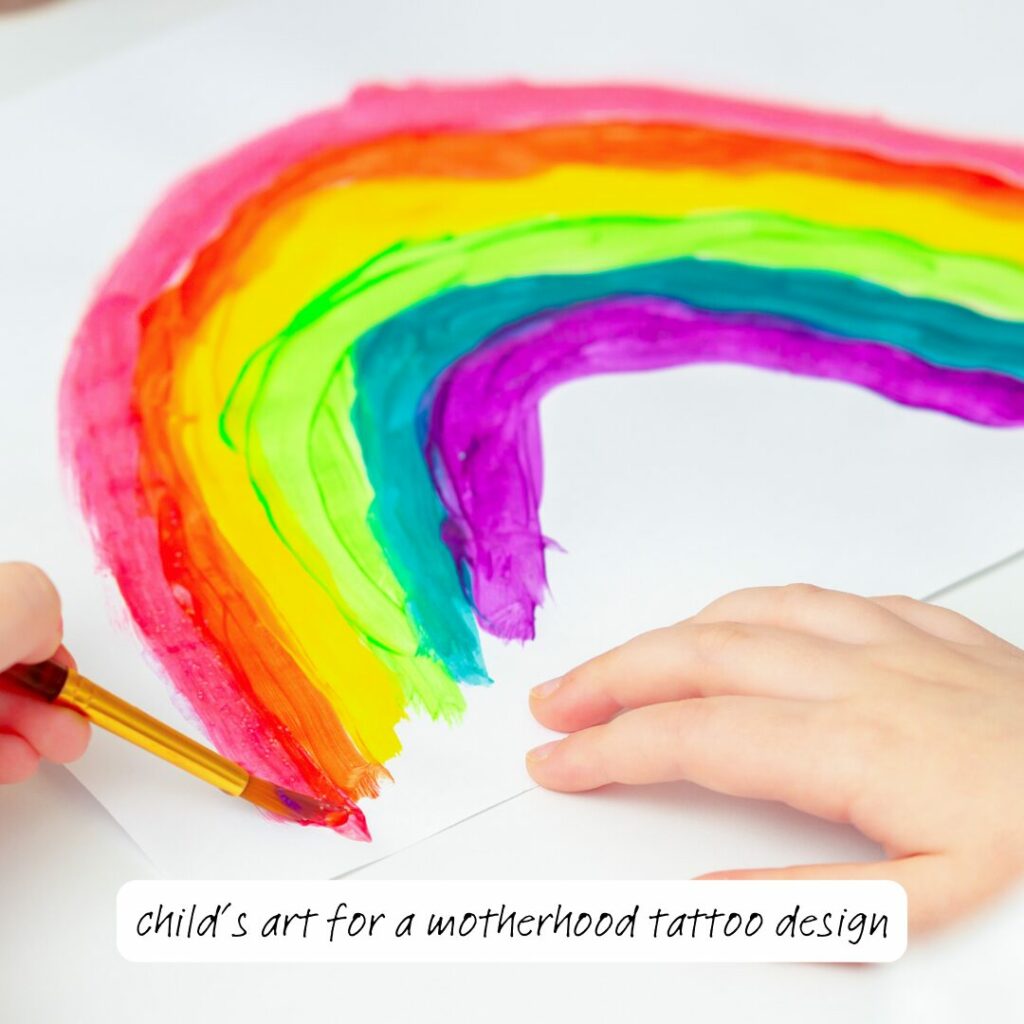 There are two small child hands painting the end of a rainbow with a paintbrush. 