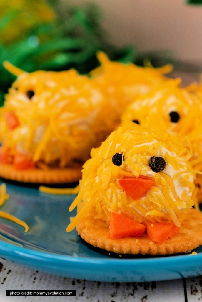 cheese balls on a plate made to look like little chicks using carrots for a beak and feet. 