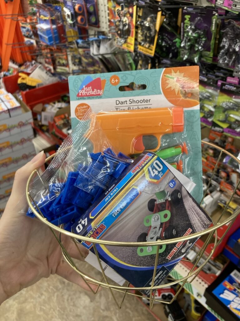 a basket of toys including legos, a building set, and a dart gun