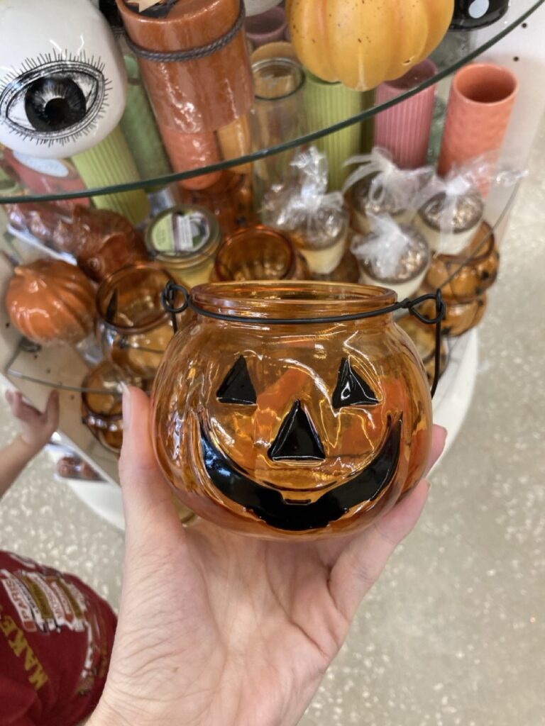 a glass pumpkin cnadle holder being held by a hand