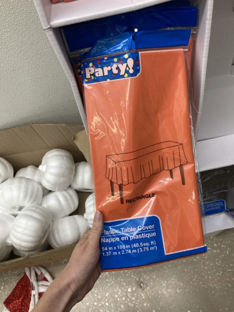 a pack of orange table cloth being held up by a hand