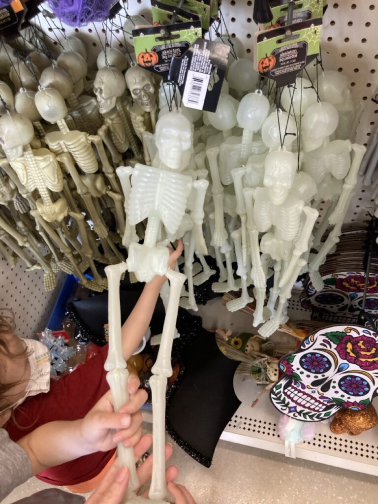 plastic skeletons hanging from the shelf at the dollar store