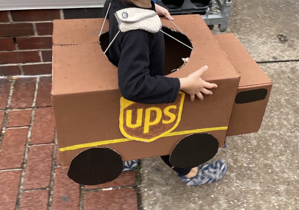a homemade UPS truck costume made of boxes with toddler arms holding it up