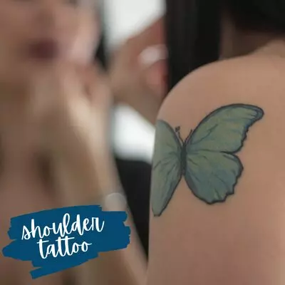 a blue butterfly tattoo on a shoulder