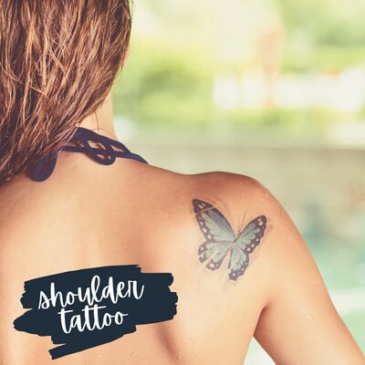 the back of a woman's shoulder with a blue butterfly tattoo on it