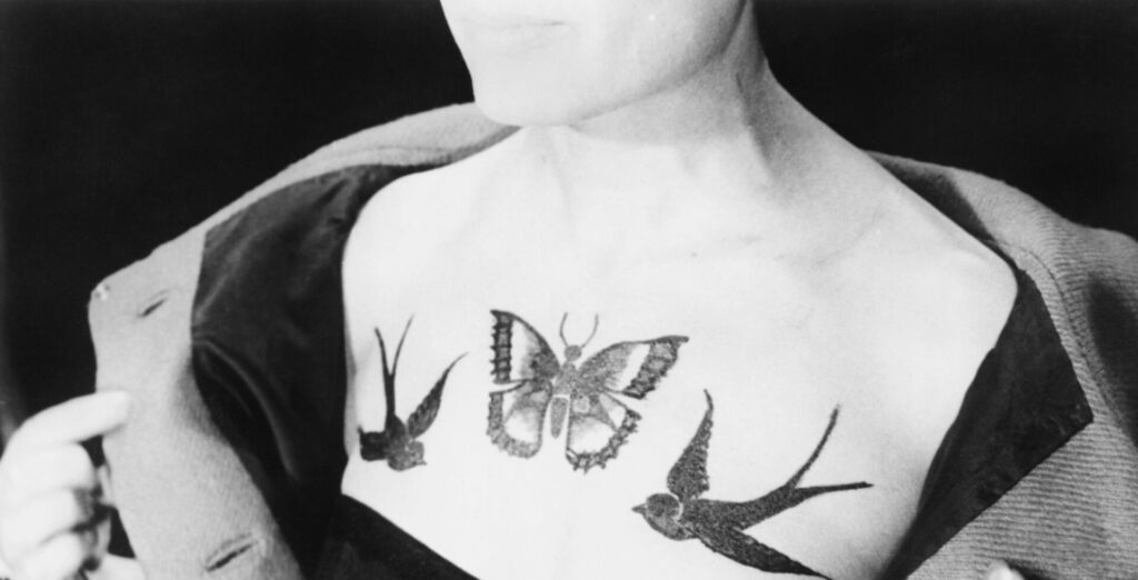 a woman's chest with a butterfly and two bird tattoos