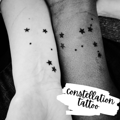 black and white photo of two arms with a star tattoos that together make a constellation