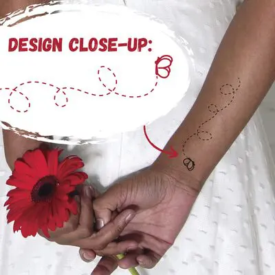 zoomed in on hands holding a flower behind the back with a butterfly tattoo on the wrist. text overlay says design close up with the simple butterfly tattoo