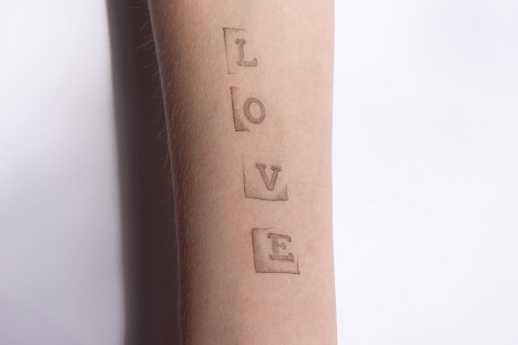 tattoo of scrabble pieces on arm that spells love