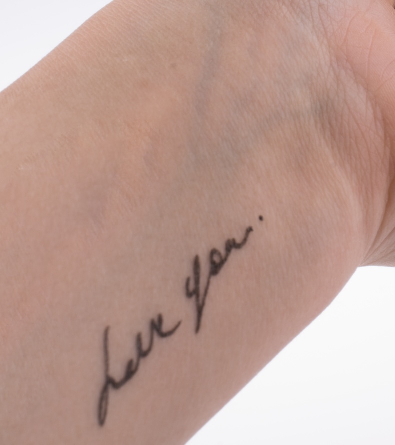 a wrist tattto of love you in cursive slightly off center
