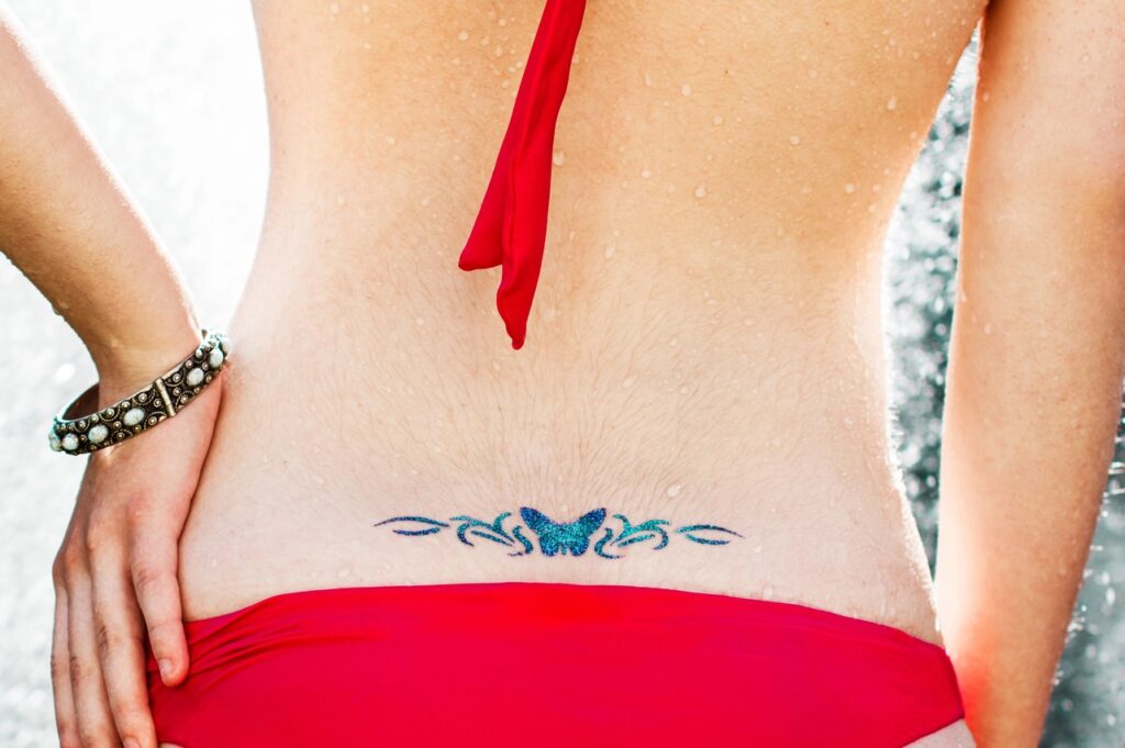 back of woman with butterfly lower back tattoo