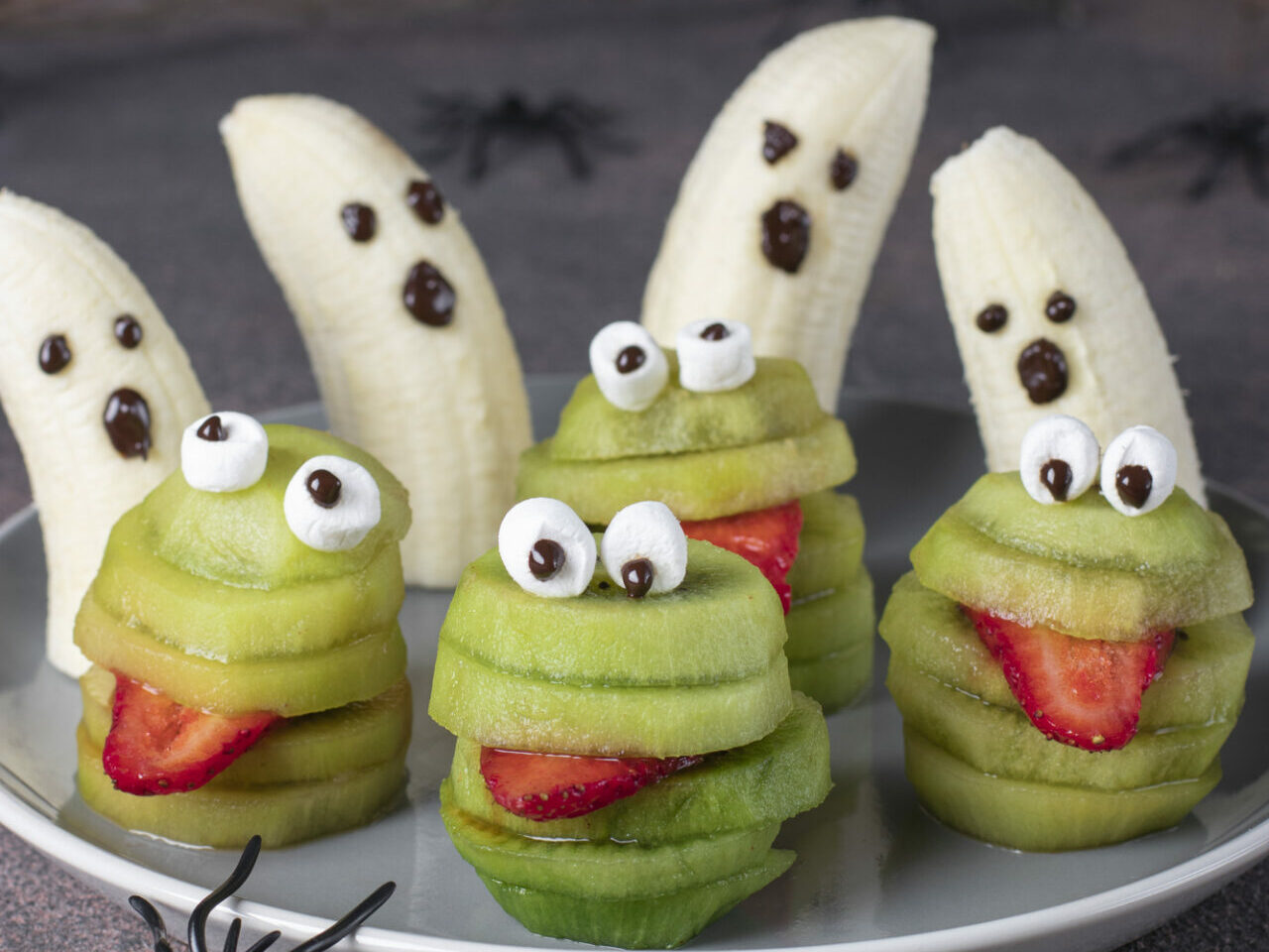 kiwis cut to look like creatures with a strawberry slice tongue, and bananas with little faces to look like ghosts