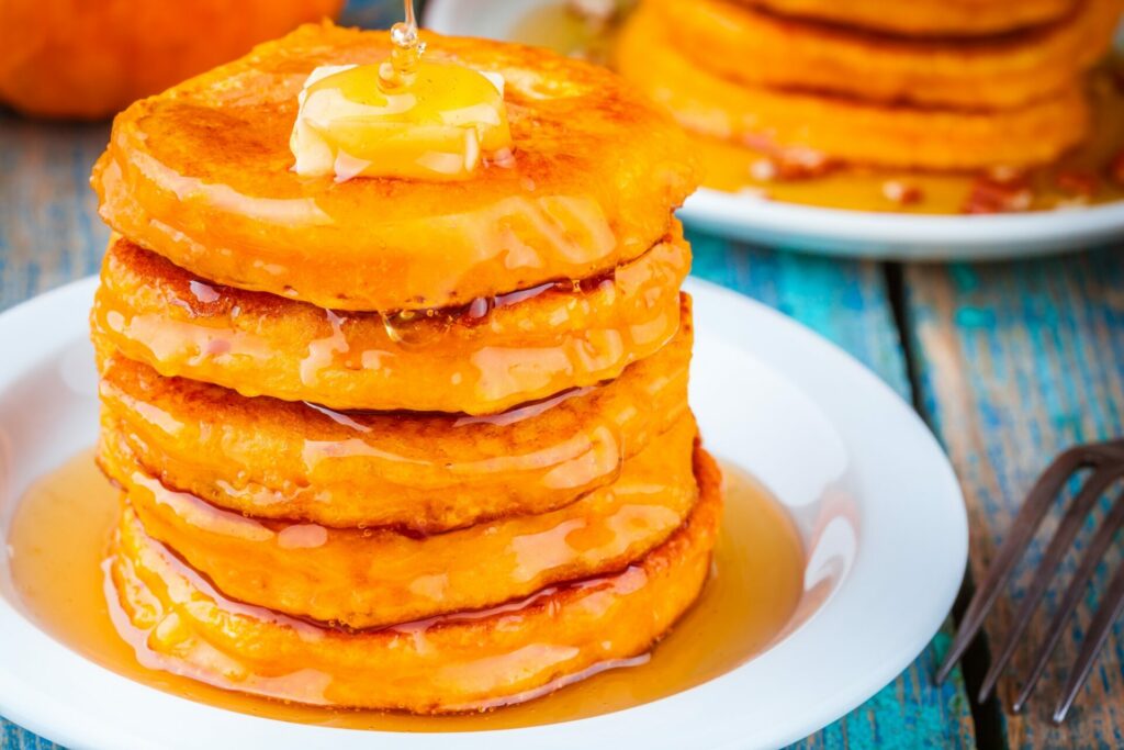 stack of pumpkin pancakes with butter and syrup on top