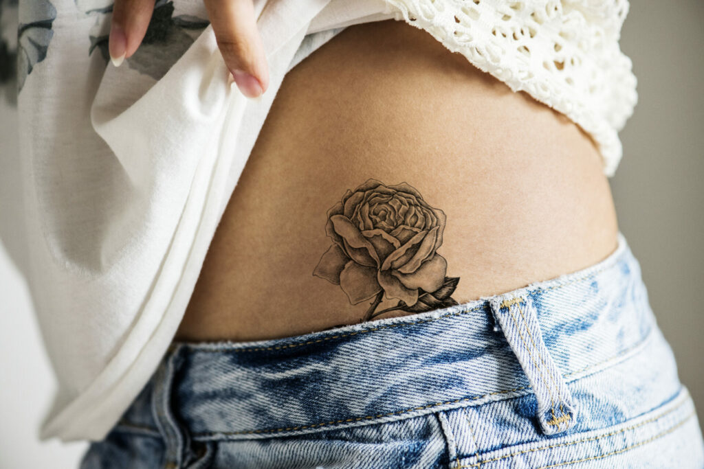 a rose hip tattoo seen above the top of jeans
