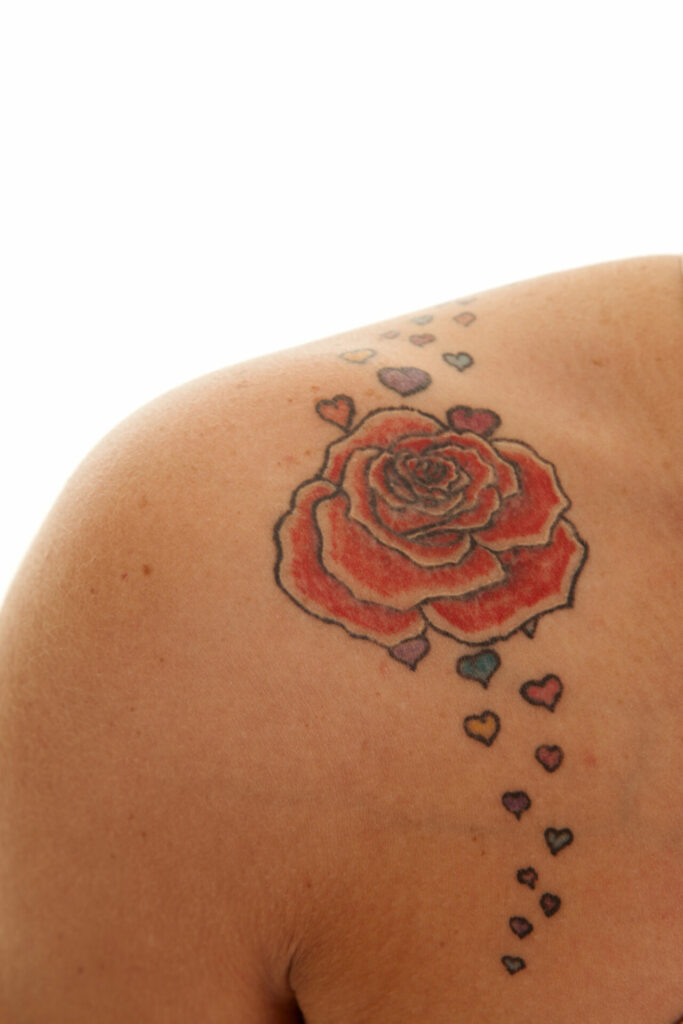 a red rose shoulder tattoo with little hearts around it