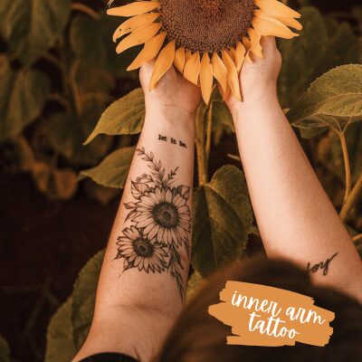 looking down at the forearms holding a sunflower with sunflower tattoos on one arm