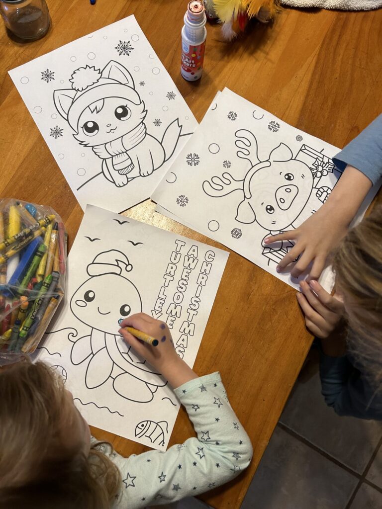 looking down on little kids coloring on cute christmas coloring sheets at a table