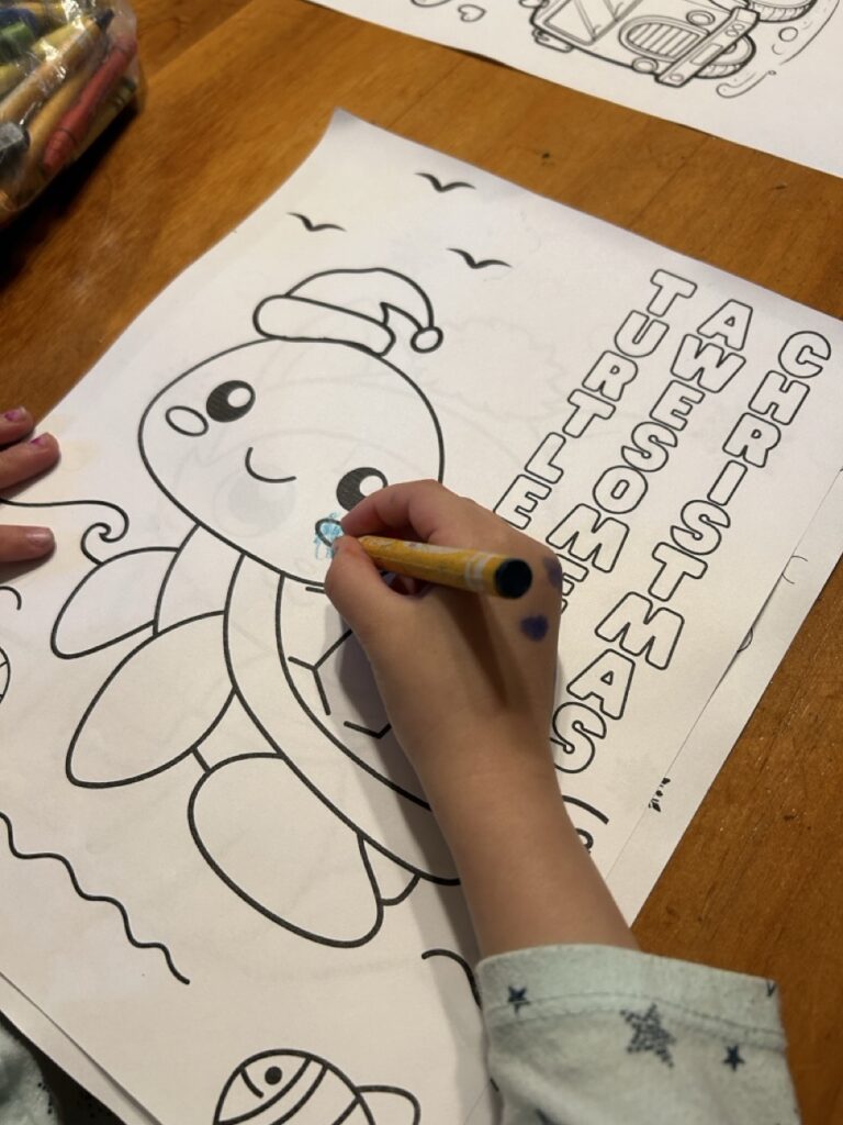 looking down on a little kid hand coloring on a christmas turtle coloring page