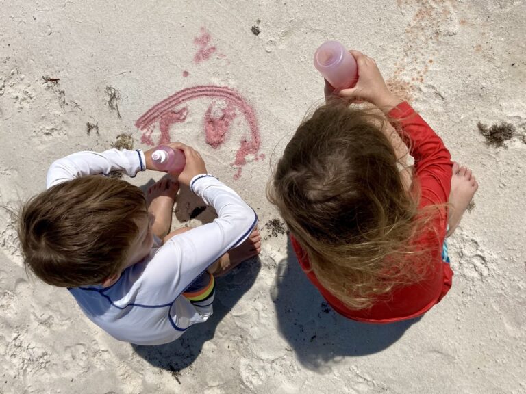 kids squirting colored water on the sand at the beach